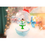Small snow globe with a snowman inside, held by a hand against a blurred festive background.