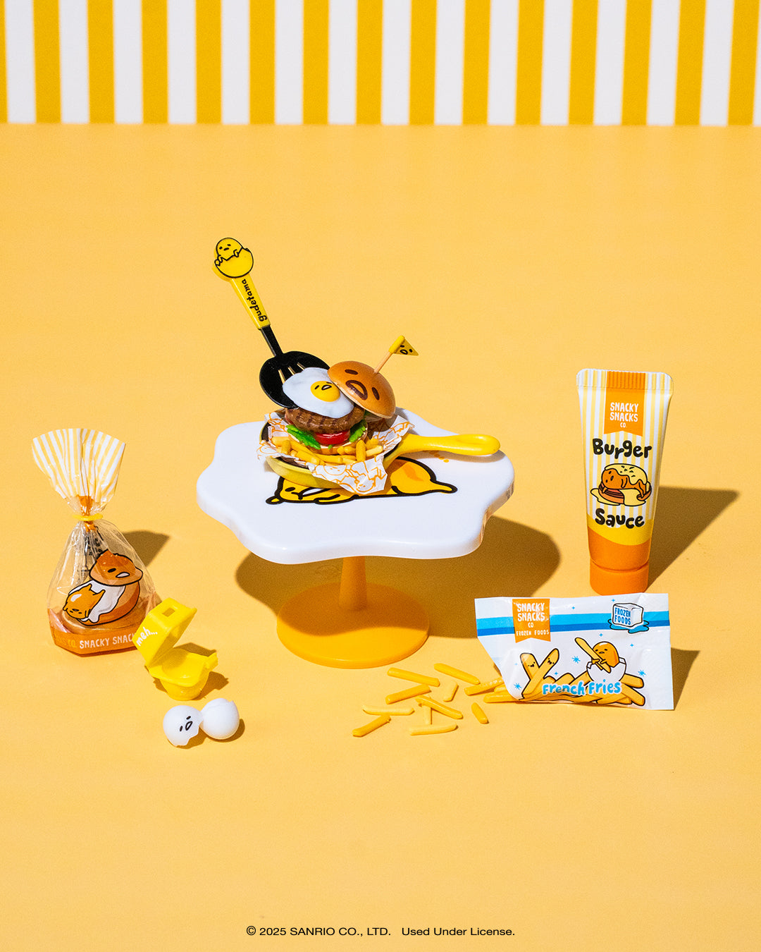 Miniverse Gudetama Cartoon character with a burger and side dishes on a yellow background