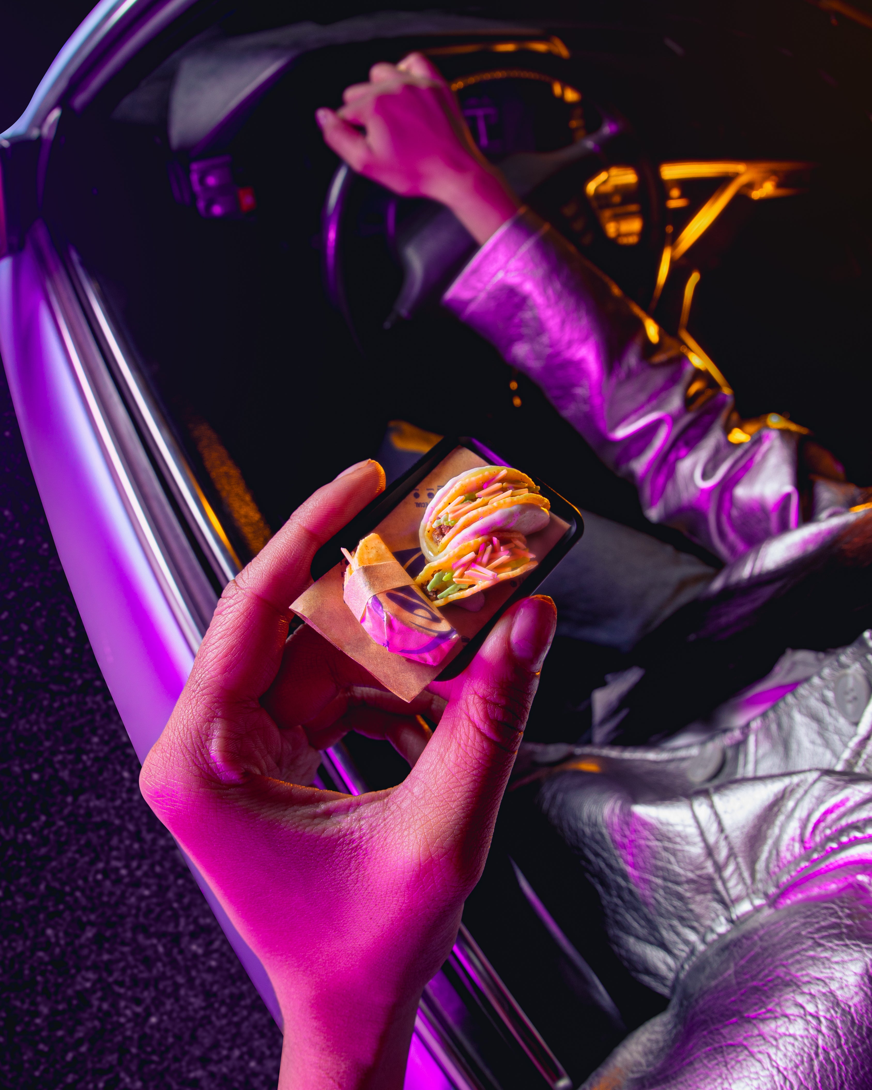 Person holding Miniverse Taco Bell tacos with a colorful snack in front of a car interior