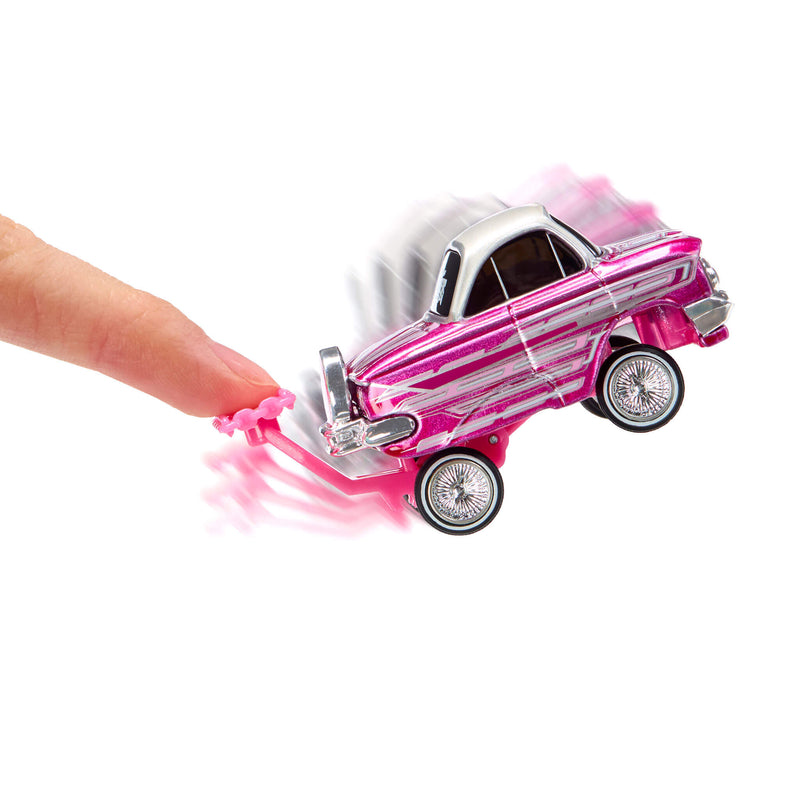 A small pink toy car with silver stripes and chrome wheels being pushed by a human finger against a plain white background.