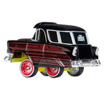 A die-cast metal model car of a classic 1957 Chevrolet station wagon, featuring a black body with red and silver pinstripes, and red spoked wheels with white-wall tires, shown on a white background.