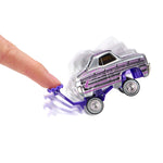 A small toy car with a silver body, being pushed by a human finger on a plain white background.