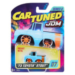 MGA Cartuned JDM '73 Toyota Stout Series 6 diecast metal toy truck in its original blister card packaging. The toy truck is light blue with orange wheels.