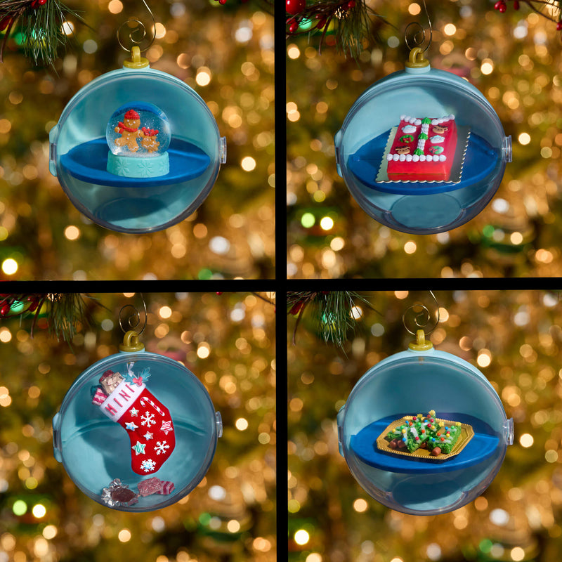 Four panels with ornaments: top left has a gingerbread snow globe inside, top right has a holiday cake inside, bottom left has a stocking inside and bottom right has Christmas trees inside. Background is blurred gold sparkle.
