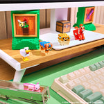 A close-up of a desk setup featuring small blocky figurines inspired by Minecraft, including a chicken, a dog, a sheep, and a cow, arranged on a white monitor arm and desk shelf alongside a keyboard and monitor.