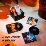 Four mini vinyl records with covers on a table, including a black crate with a photo of a woman.