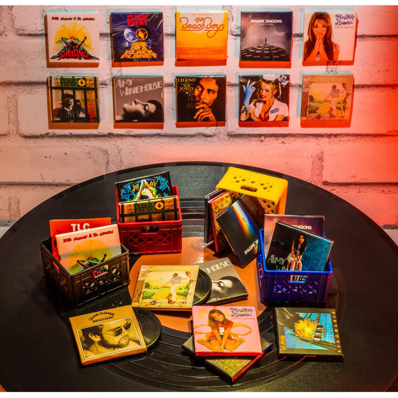 Collection of vintage mini record albums displayed on a table with a brick wall background.