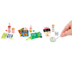 Mini grocery items set straight across a white background, with a hand holding a knife in cheese.