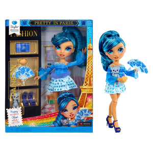 Fashion doll with blue hair and outfit, holding a puppy and a fan, next to its packaging