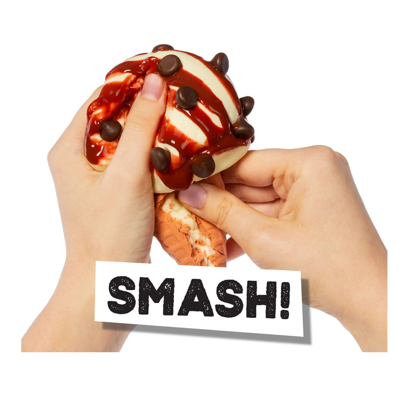 Two hands squeezing a squishy toy shaped like a chocolate ice cream sundae with red drizzle and dark chocolate chips, with a white label reading 'SMASH!' overlaid at the bottom on a white background.