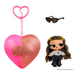 Small doll with brown hair and sunglasses with a heart shape keychain on a white background