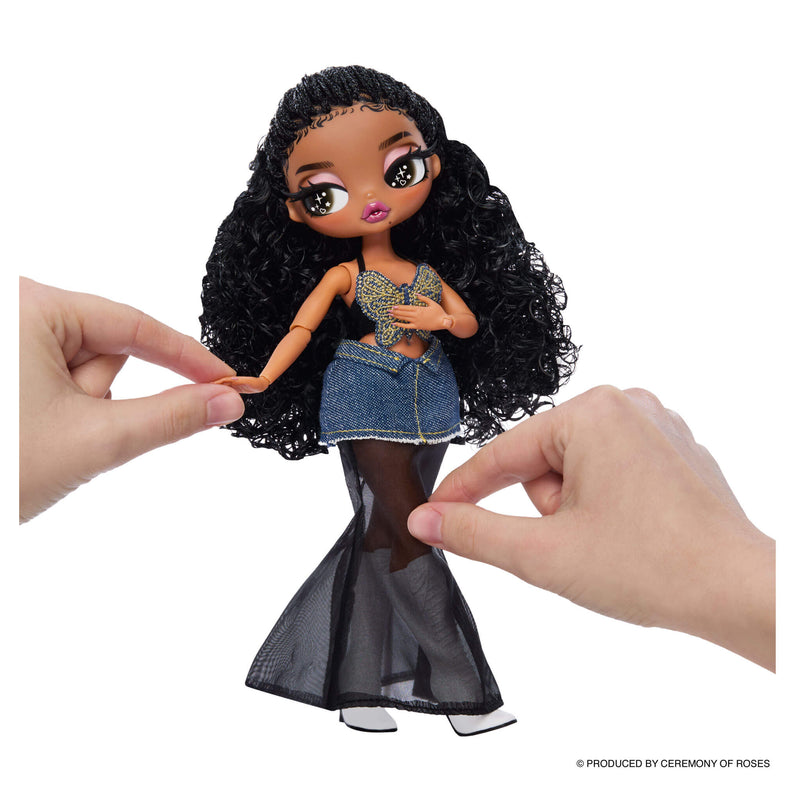 Hands posing the doll, left hand is holding the dolls hand while the right hand is fixing the sheer part of the skirt.