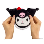 Plush toy with a skull design held by hands on a white background