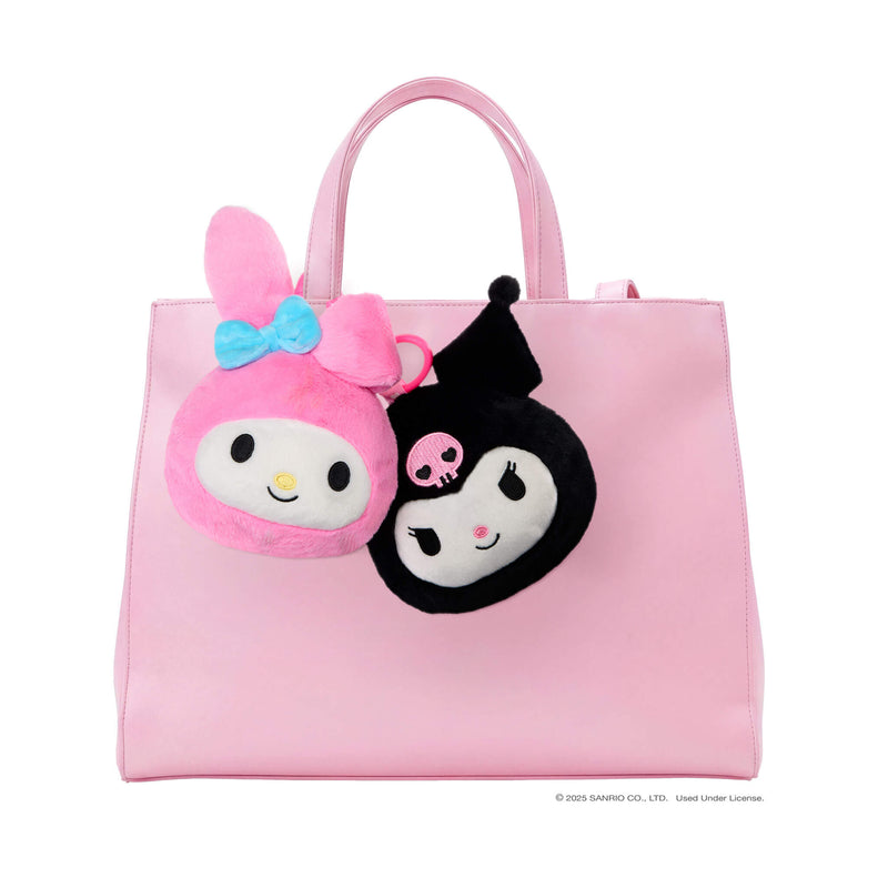 Pink tote bag with two Hello Kitty  faces clipped onto the handle on a white background