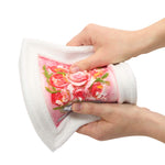 A close-up of the picture being squeezed by two hands, showing a pink floral pattern on the inner side, against a plain white background.
