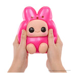 Pink squishy toy with a face held between two hands on a white background