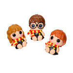 Three figurines of a boy, girl, and another boy in Harry Potter-themed outfits on a white background