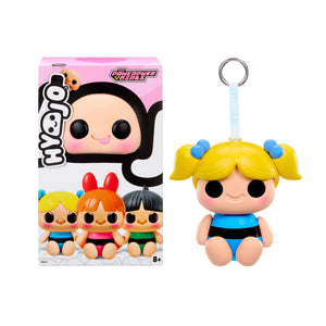 Toy figure with blonde hair and blue outfit next to its packaging on a white background