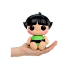 Toy figure with black hair and green outfit held in a hand on a white background