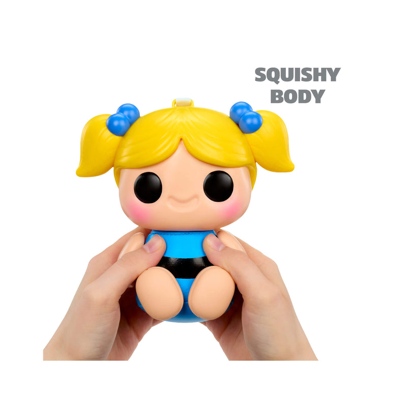 Toy figure with blonde hair and blue pigtails held by a hand, labeled 'Squishy Body' on a white background.