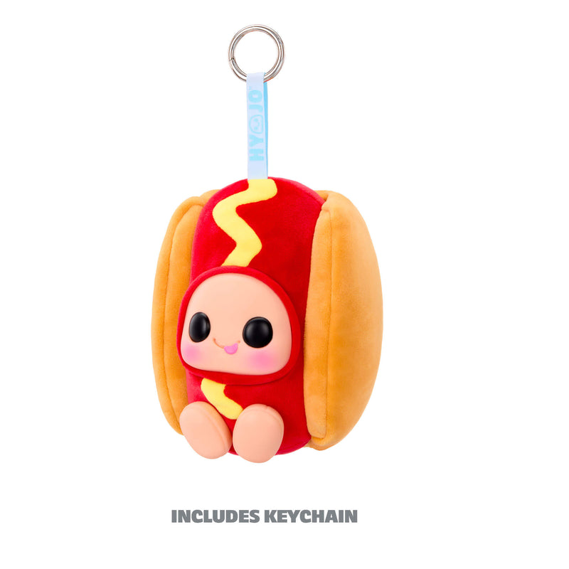 A plush hot dog character keychain with a cute smiling face, red and yellow outfit, tan bun, and a silver keyring at the top on a white background. Text below reads 'INCLUDES KEYCHAIN'.