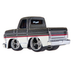 A die-cast toy custom lowrider pickup truck, styled like a vintage Chevy with a black glitter-flecked top, a white lower body, a red stripe, and chrome wheels, shown on a white background.