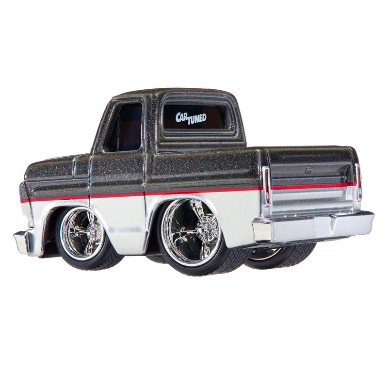 A die-cast toy custom lowrider pickup truck, styled like a vintage Chevy with a black glitter-flecked top, a white lower body, a red stripe, and chrome wheels, shown on a white background.