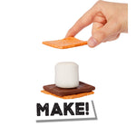 A hand is holding an cracker above a stacked s'mores made of a cracker, a brown chocolate piece, and a white marshmallow. The word 'MAKE!' appears below on a white background.