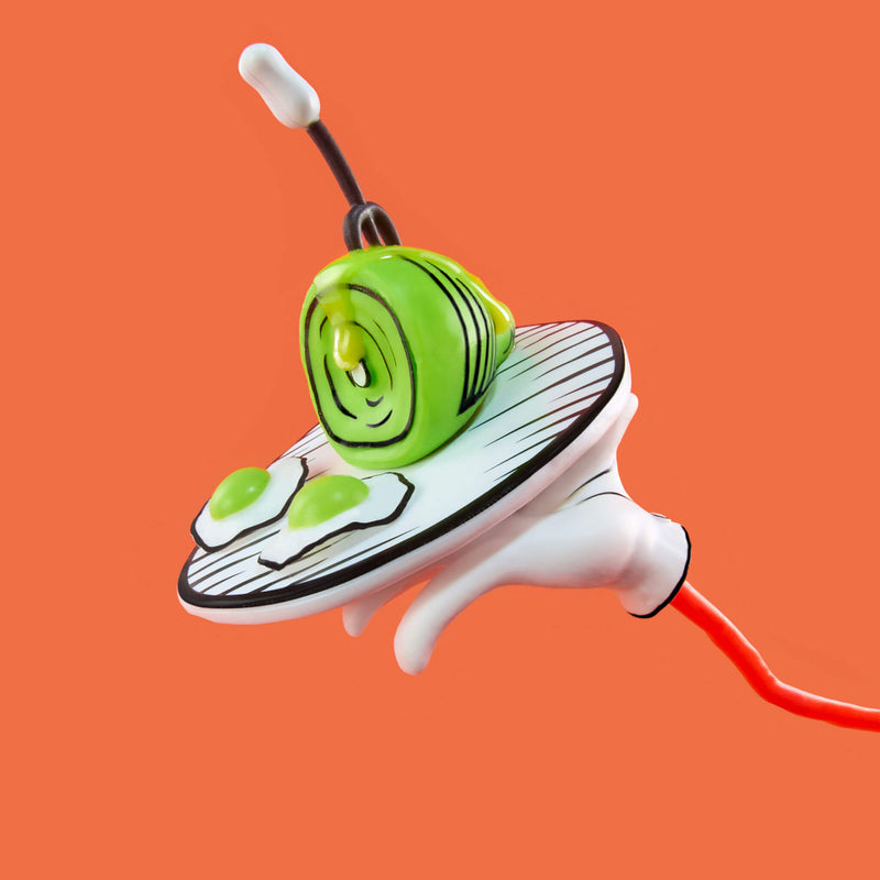 White and black tray with green eggs, green ham and a fork, shown against a solid orange background.