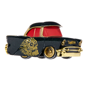 A toy car styled like a classic 1957 Chevrolet, featuring a black glitter body, gold flame skull decal, red windows, and gold chrome details, shown against a plain white background.