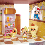 A doll playset kitchen scene with three small dolls standing in front of a toy refrigerator and a counter, set against a printed kitchen backdrop. The dolls wear pastel yellow outfits, and the refrigerator contains small toy food items.