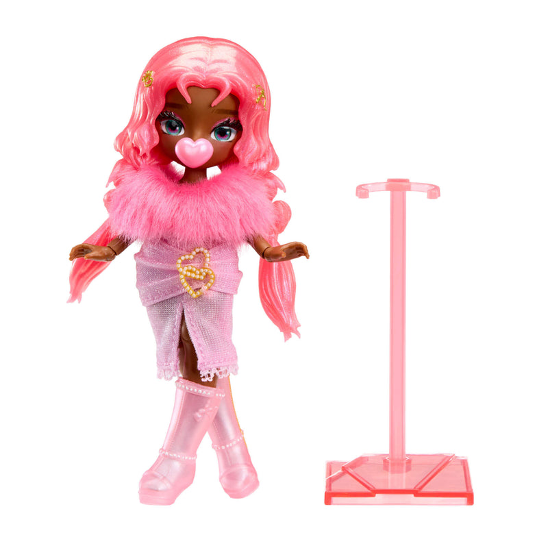 A doll with long pink hair, blowing a heart shaped bubble stands on a white background wearing a pink dress, and pink boots. To the right is a pink doll stand.