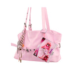 Pink purse with Mini Mi in packaging keychain hanging from a strap on a white back ground.