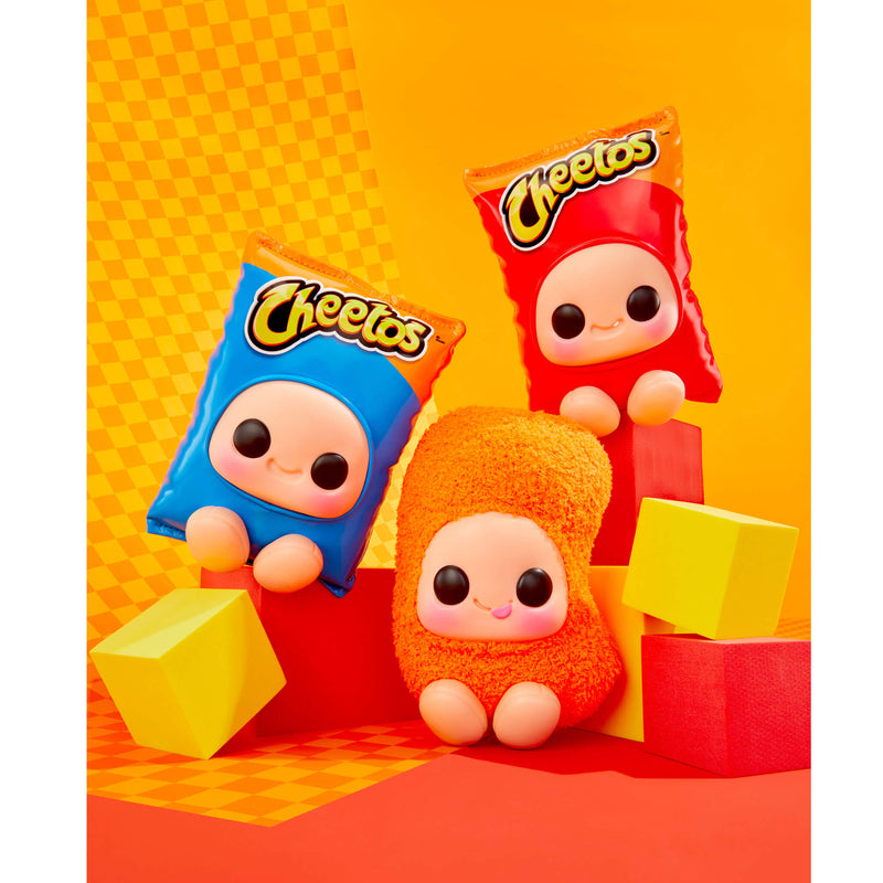Three Cheetos character plush toys two are shaped like snack bags, shown in blue, red, and orange, styled with yellow and red blocks against a bright orange and yellow background.