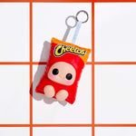 A Cheetos-themed plush keychain bag shaped like a red snack bag with a cartoon face and a keychain, photographed on a white background with orange grid lines.
