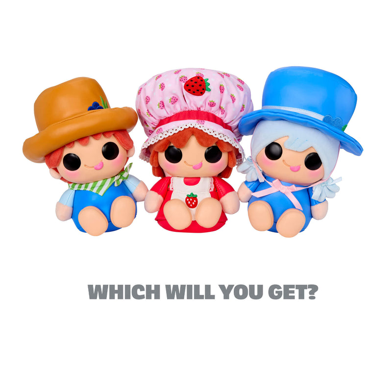 Three Strawberry Shortcake cartoon characters with large black eyes are shown side by side on a plain white background. The left doll wears a brown hat and blue outfit with green accents, the middle doll is Strawberry Shortcake, the right doll wears a blue hat, and a blue outfit. With text at the bottom, WHICH WILL YOU GET?’