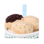 Three toy donuts with different toppings on a white plate with a polka dot border.