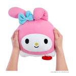 Hands holding a pink looking stuffed bunny with a blue bow and a smiley face, the bottom is showing a little white and red on a white background.