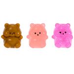 Three small bear-shaped squishy toys in brown, pink, and glittery pink, arranged side by side on a plain white background.