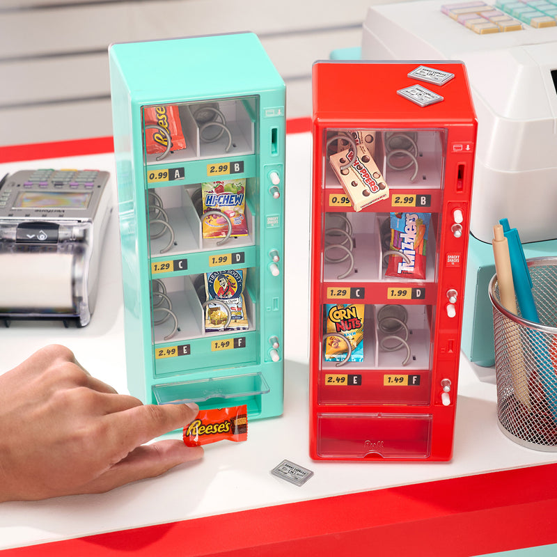 Two mini vending machine style shown side by side on a white, desk background, one red and one teal each stocked with candy and chips. 