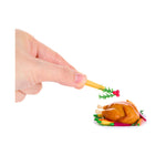 A hand putting Holly on the turkey sitting on a white platter with colorful carrots on a white background.