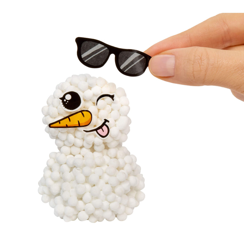 Small snowman figurine with sunglasses held by a hand on a white background
