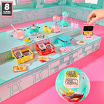 Toy kitchen set with miniature appliances and a hand reaching for a mini waffle maker, with a Mini World packaging in the foreground.