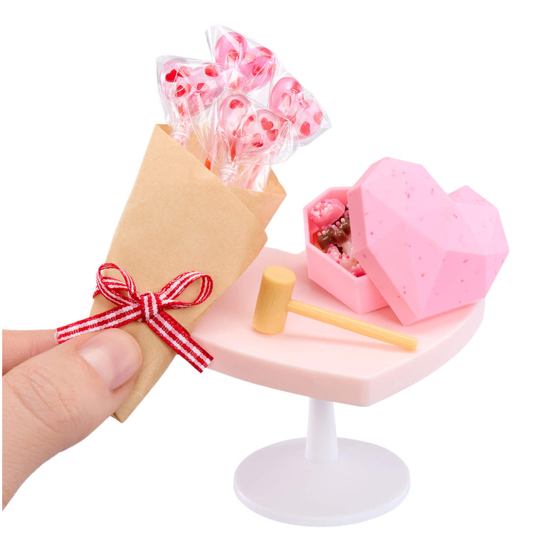 Miniature pink heart with a hammer, lollipops, and a gift on a white background