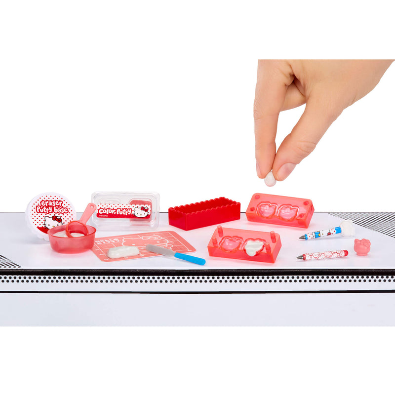 Set of small red and white items on a white surface with a hand reaching towards them.