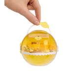 Hand holding a transparent yellow toy with a white interior, featuring a small items inside.
