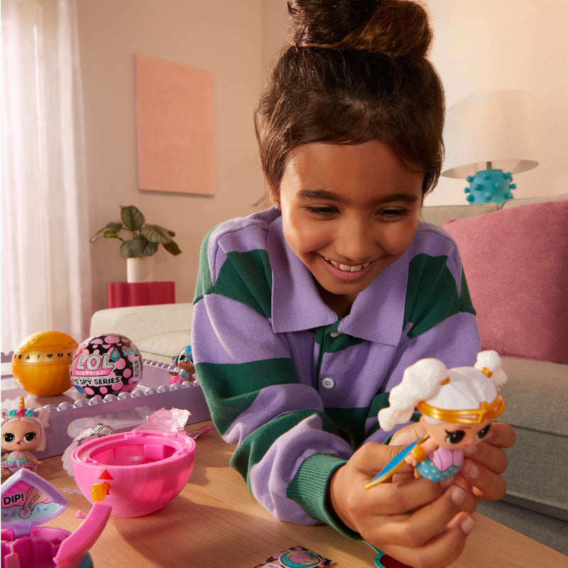 Young girl playing with a toy figure in a room with a pink couch and plant.