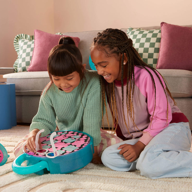 Two young girls opening the Ultimate Eye Spy Surprise  toy on the floor.