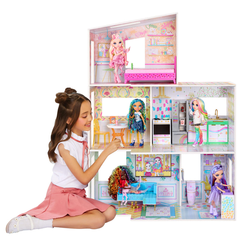 Girl playing with a dollhouse featuring multiple dolls and rooms.