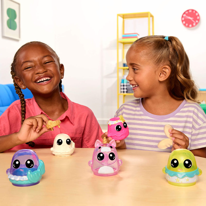Two children playing with colorful toy figures on a table, with a clock and shelf in the background.